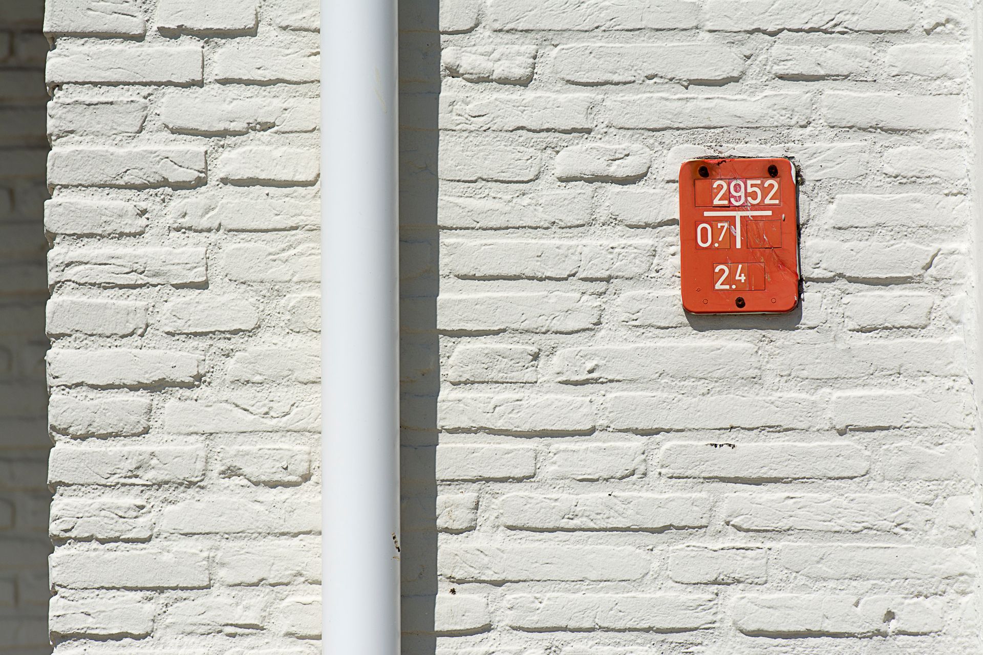 Mur de briques blanches avec un tuyau blanc vertical 