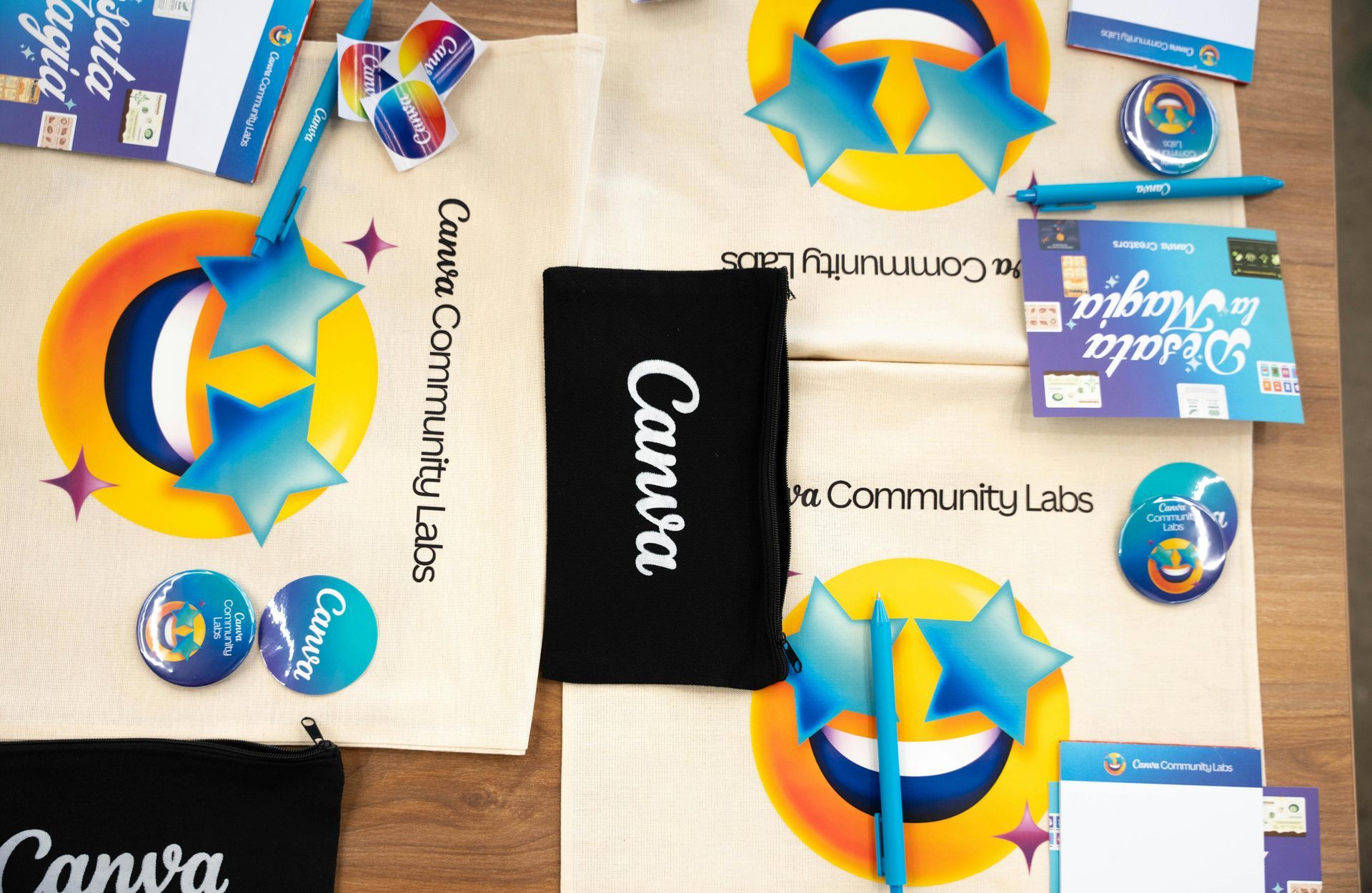 Camisetas, bolsas de tela y pegatinas de la marca Canva expuestas en una mesa.