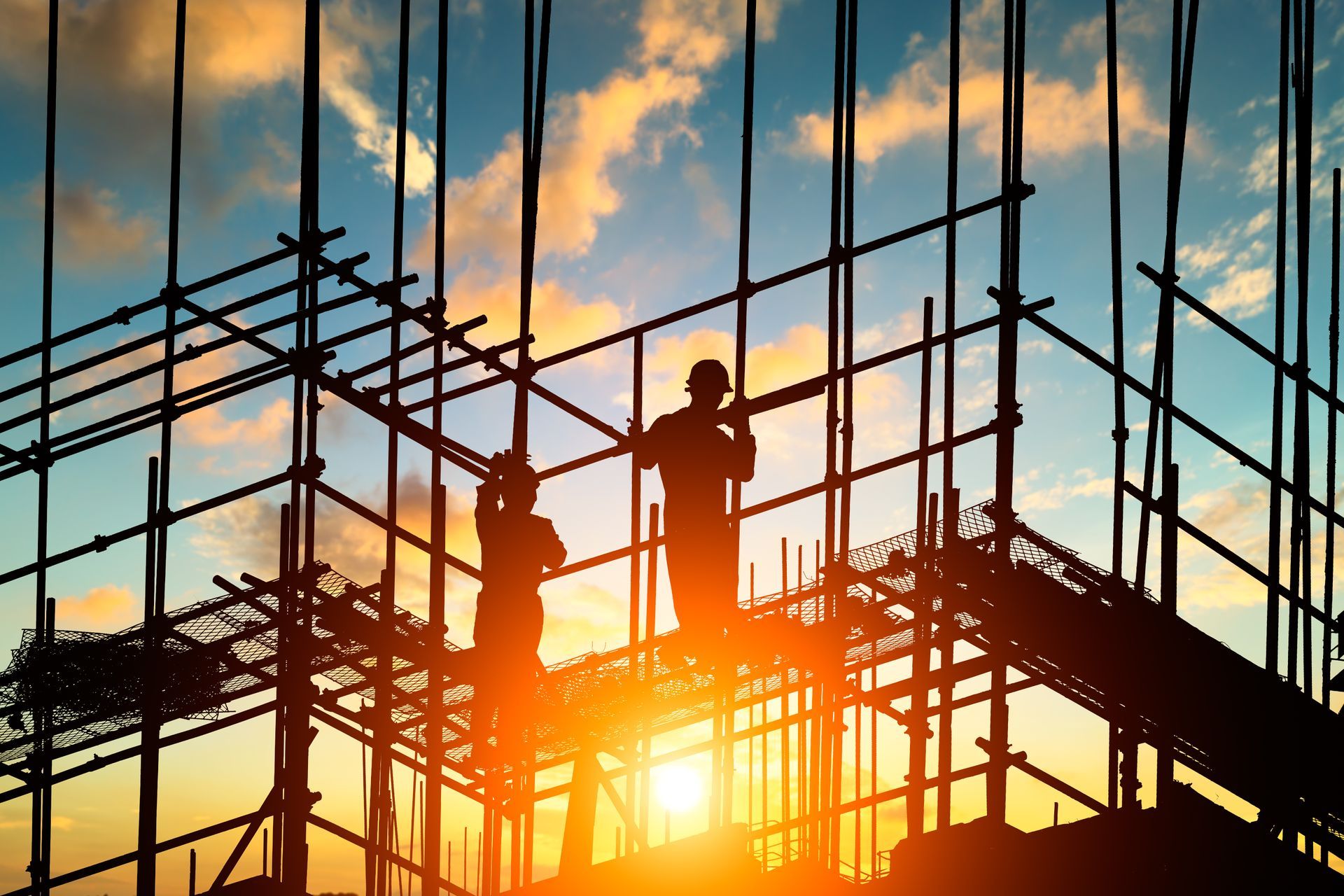 Des artisans sur un échafaudage durant le coucher du soleil