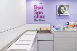 Sala de examen de clínica veterinaria con paredes de color morado y blanco, lavabo, mesa de examen y suministros.