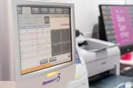 Microscopio, centrífuga y equipo de laboratorio sobre una superficie blanca.