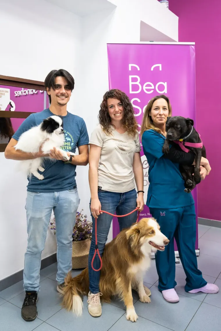 Personas con mascotas en una clínica veterinaria. Un hombre sostiene un perro pequeño, una mujer con un perro con correa