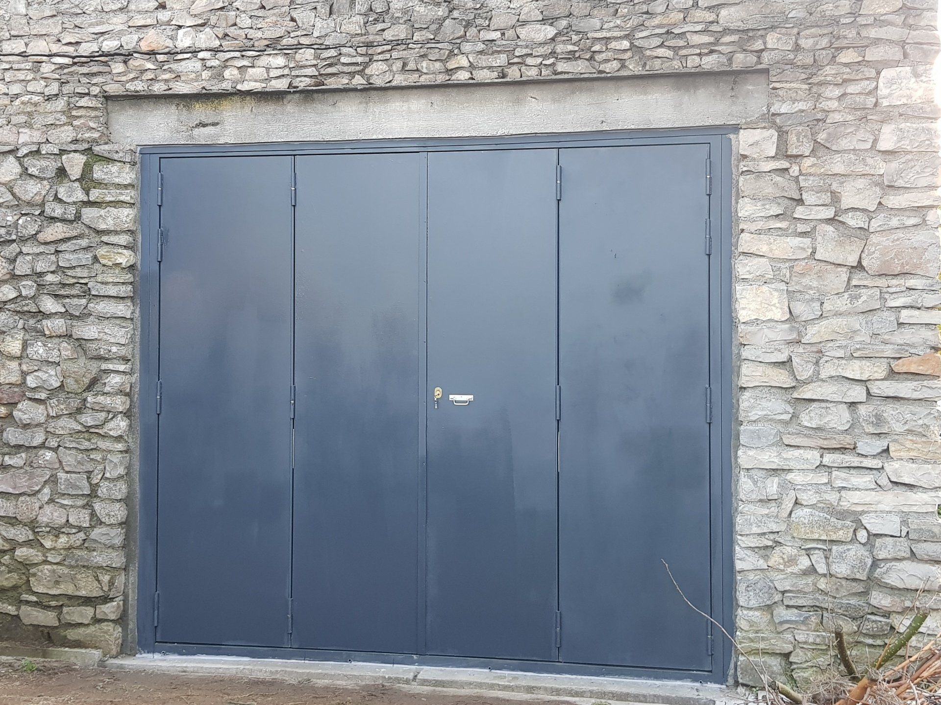 Portes en métal gris encastrées dans un bâtiment en pierre.