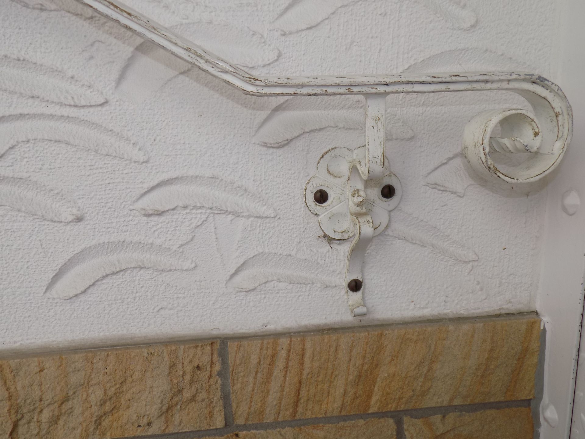 An einer Backsteinmauer ist ein weißes Geländer befestigt.