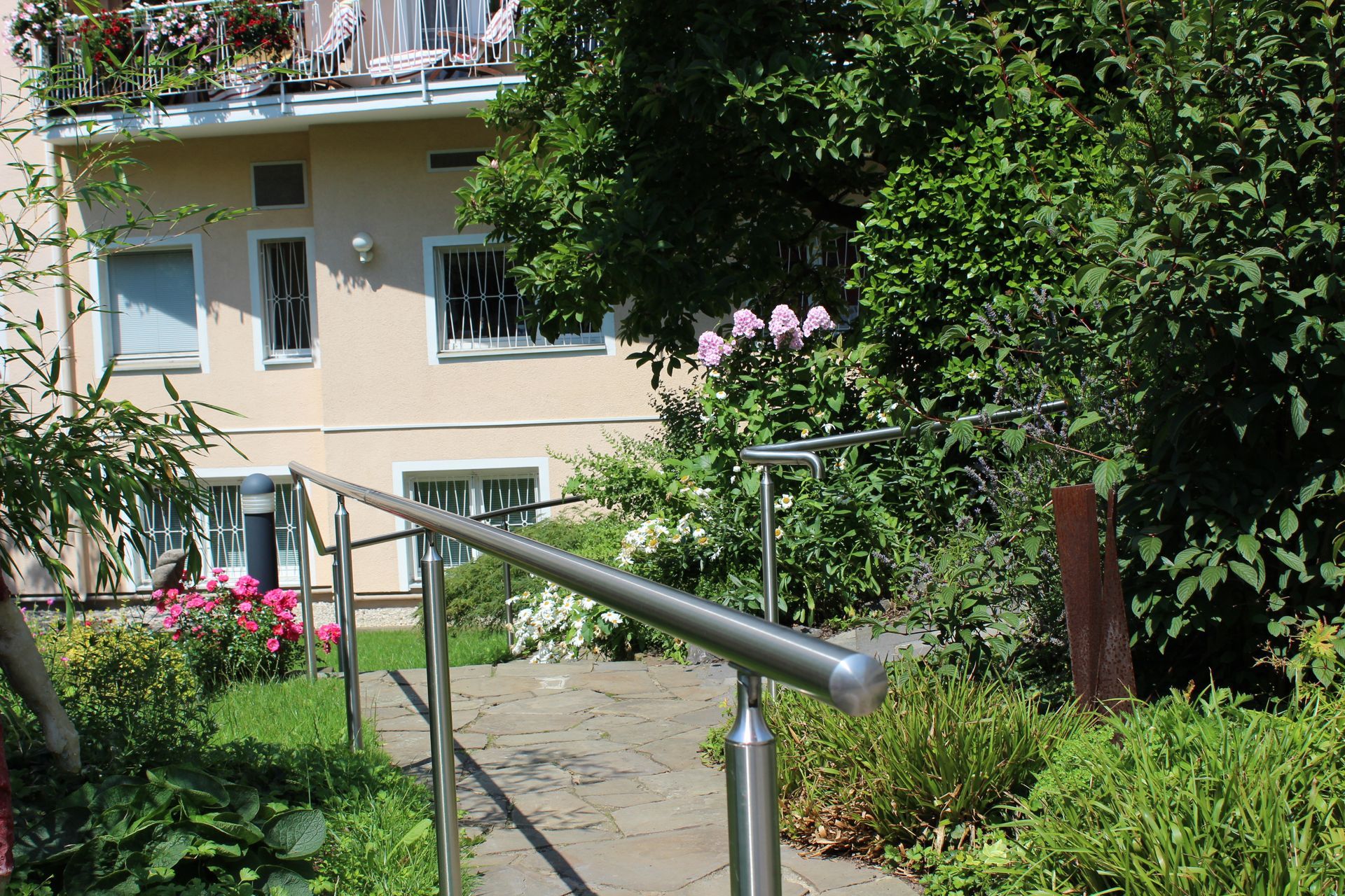 Ein Edelstahlgeländer führt zu einem Gehweg vor einem Gebäude