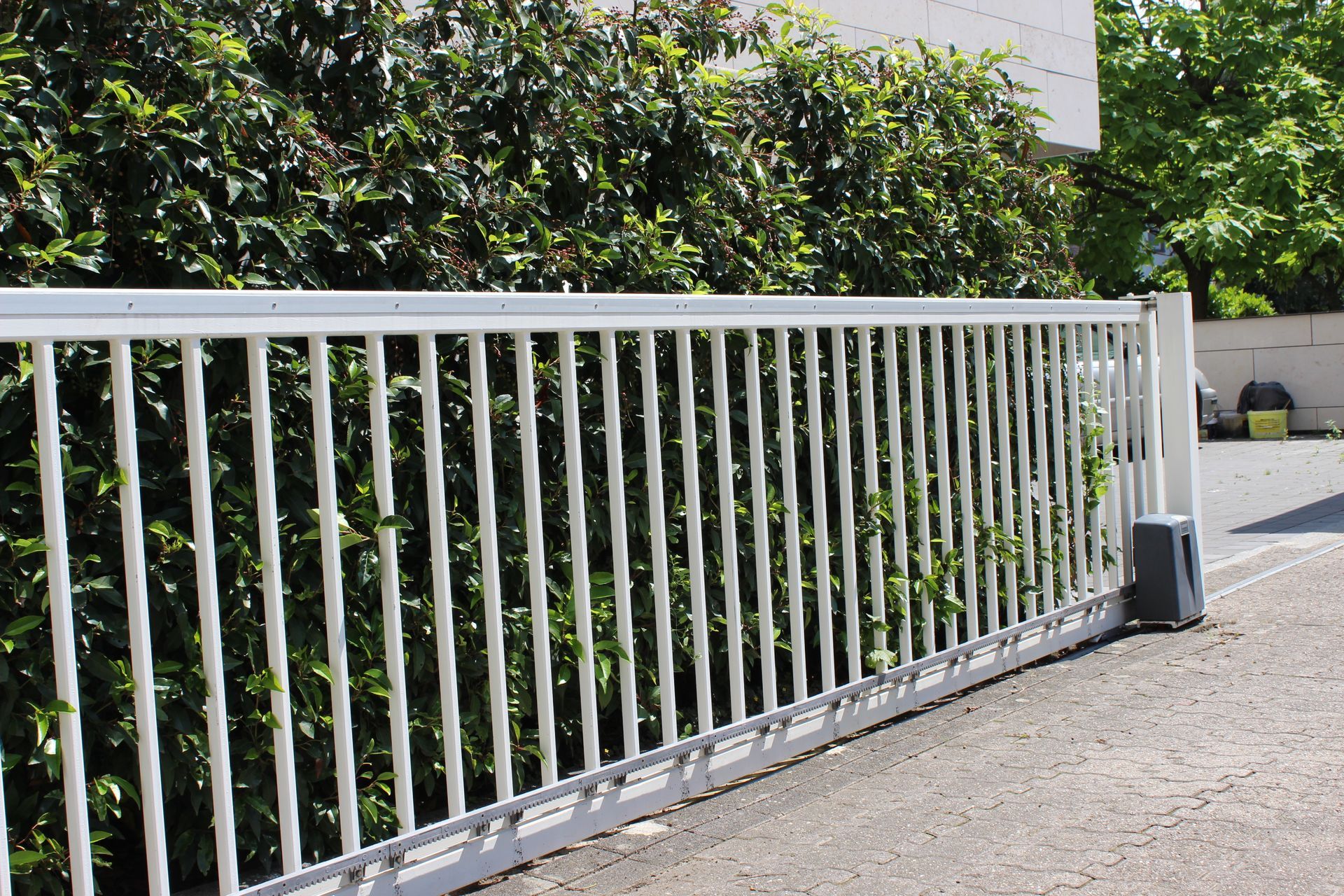 Ein weißer Zaun mit einem Schiebetor im Hintergrund