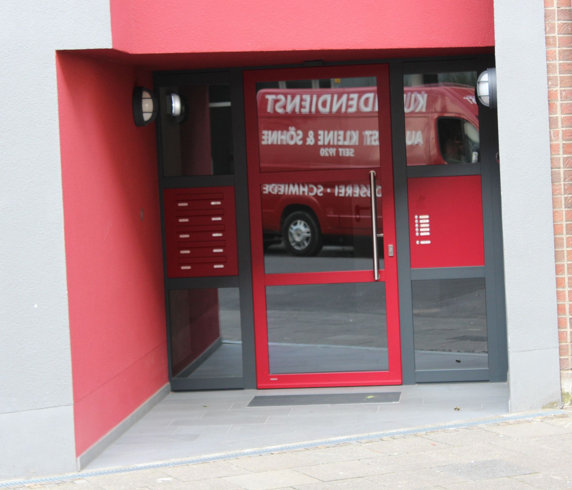 Ein rot-graues Gebäude mit einer roten Tür, auf der steht: t3i3idiei2