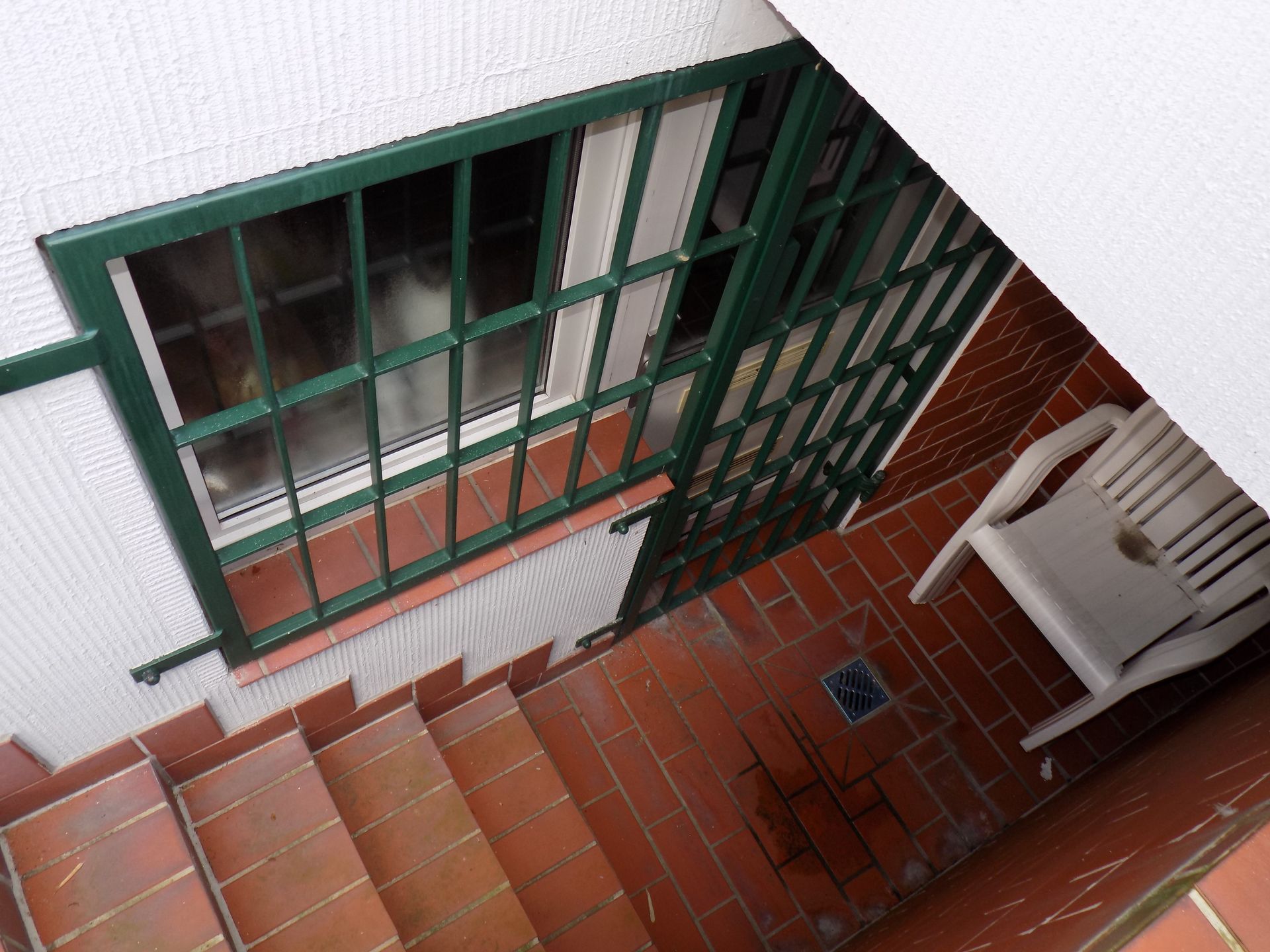 Treppe führt hinauf zu einem Balkon mit einem Stuhl und einem Fenster