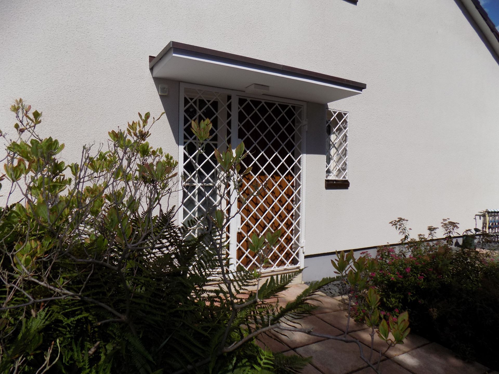 Ein weißes Haus mit einer Holztür und einem Zaun darum