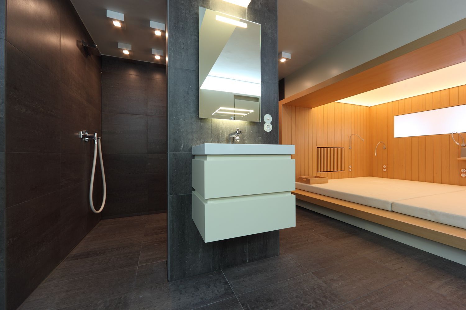 Ein Badezimmer mit Waschbecken, Spiegel und ebenerdiger Dusche