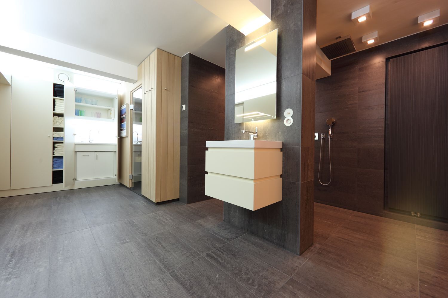 Ein Badezimmer mit Waschbecken, Spiegel und ebenerdiger Dusche.