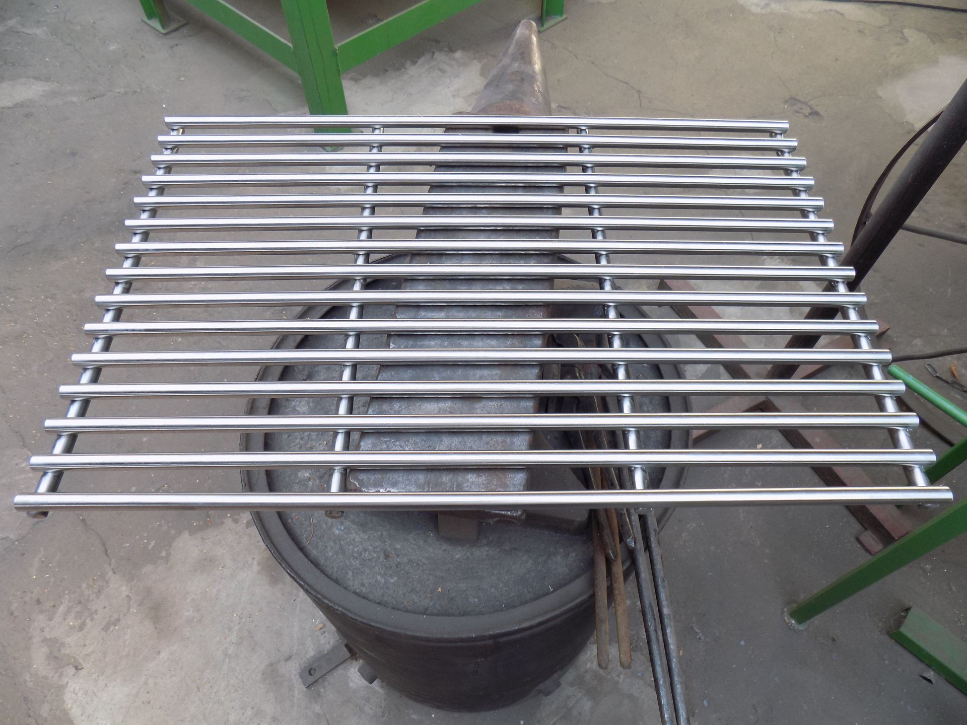 Ein Edelstahlgrill sitzt auf einem schwarzen Fass