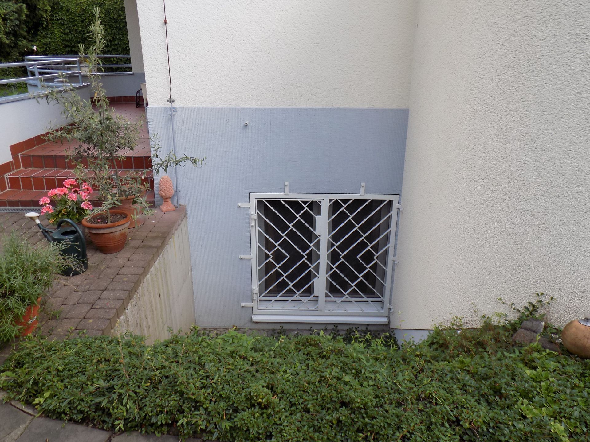 Ein weißes Gebäude mit einem Zaun um ein Fenster