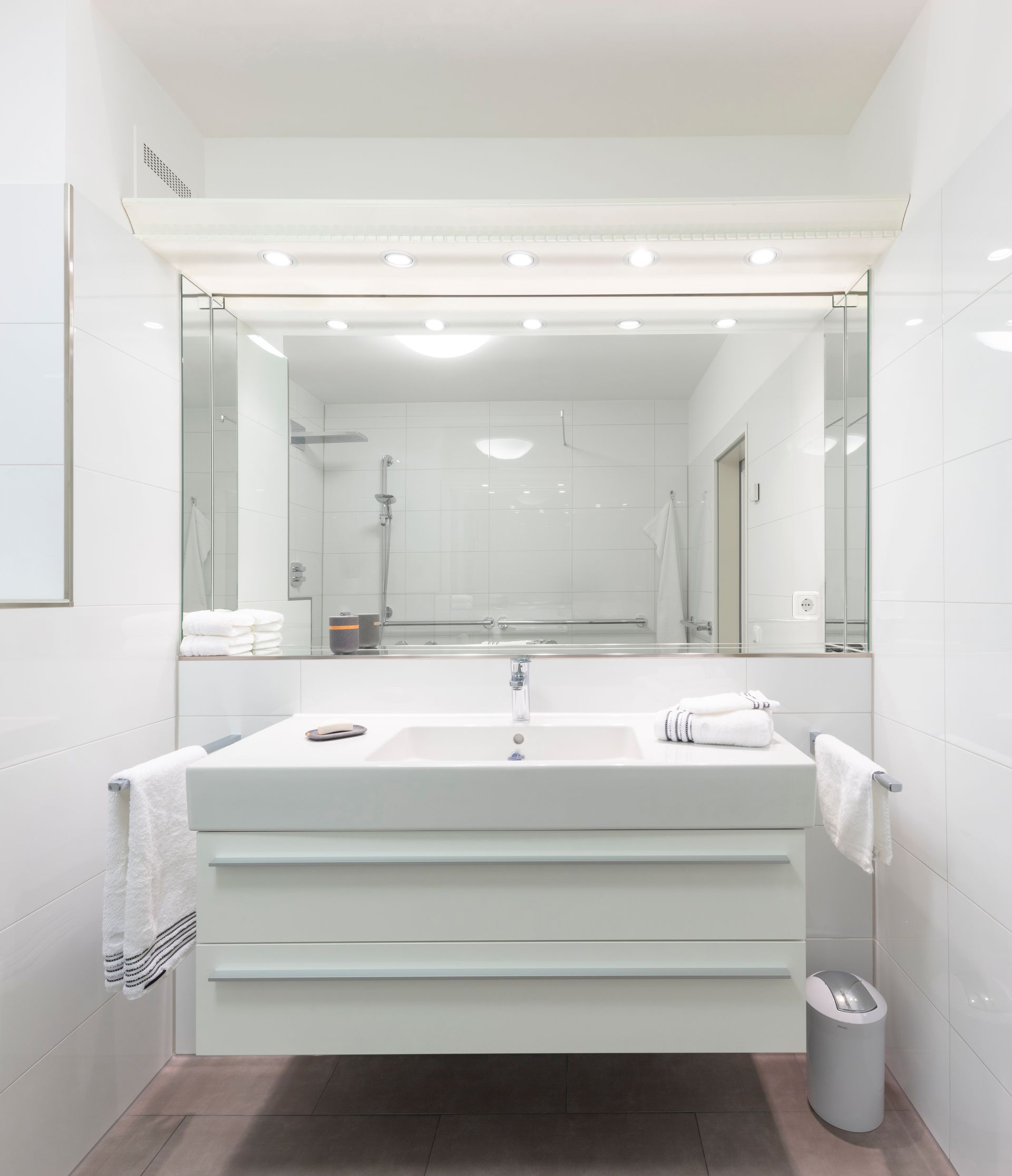 Ein Badezimmer mit Waschbecken, Spiegel und Mülleimer.