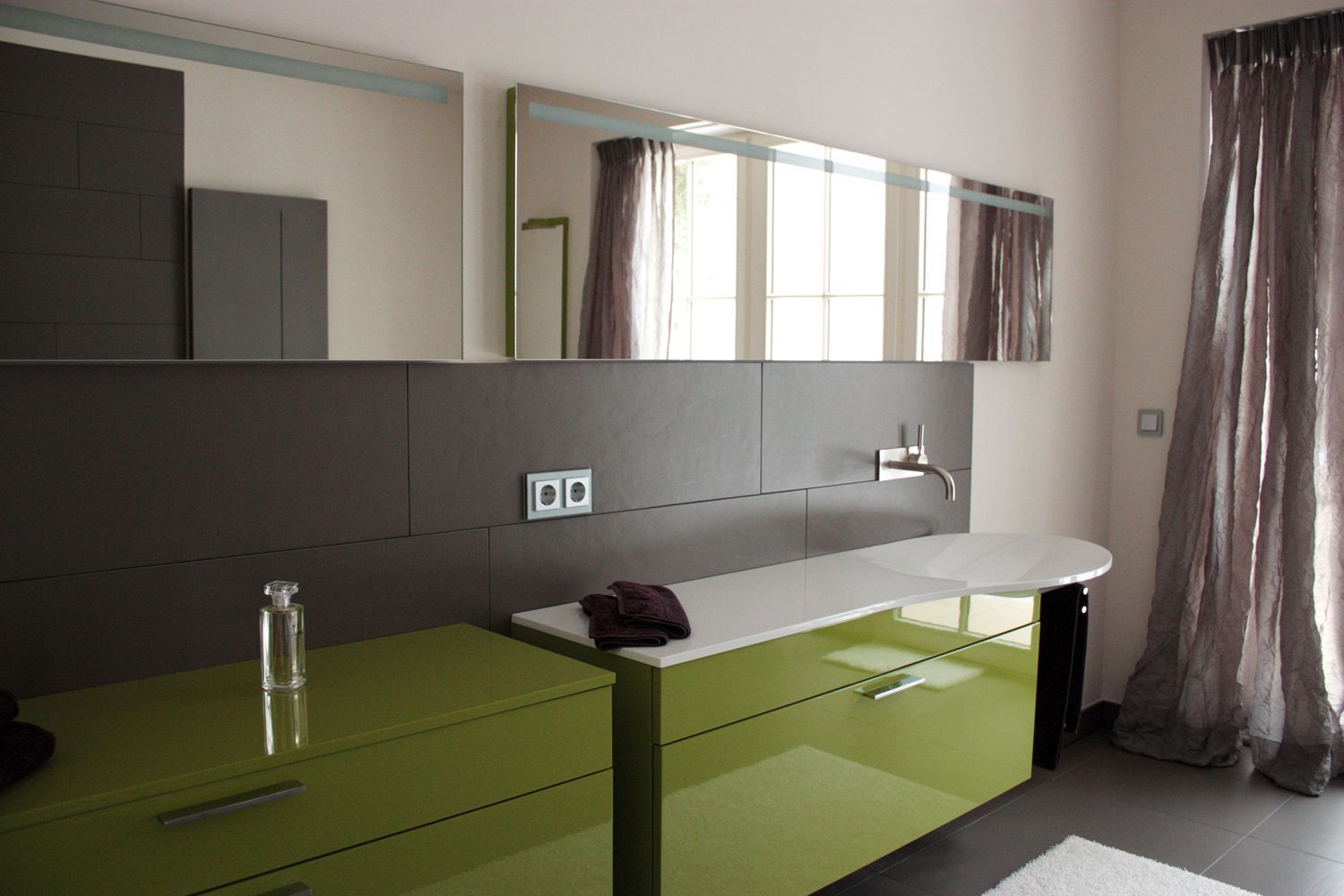 Ein Badezimmer mit grünen Schränken und zwei Spiegeln