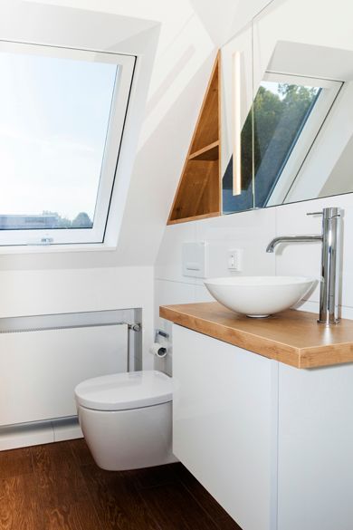 Ein Badezimmer mit Toilette, Waschbecken, Spiegel und Oberlicht.