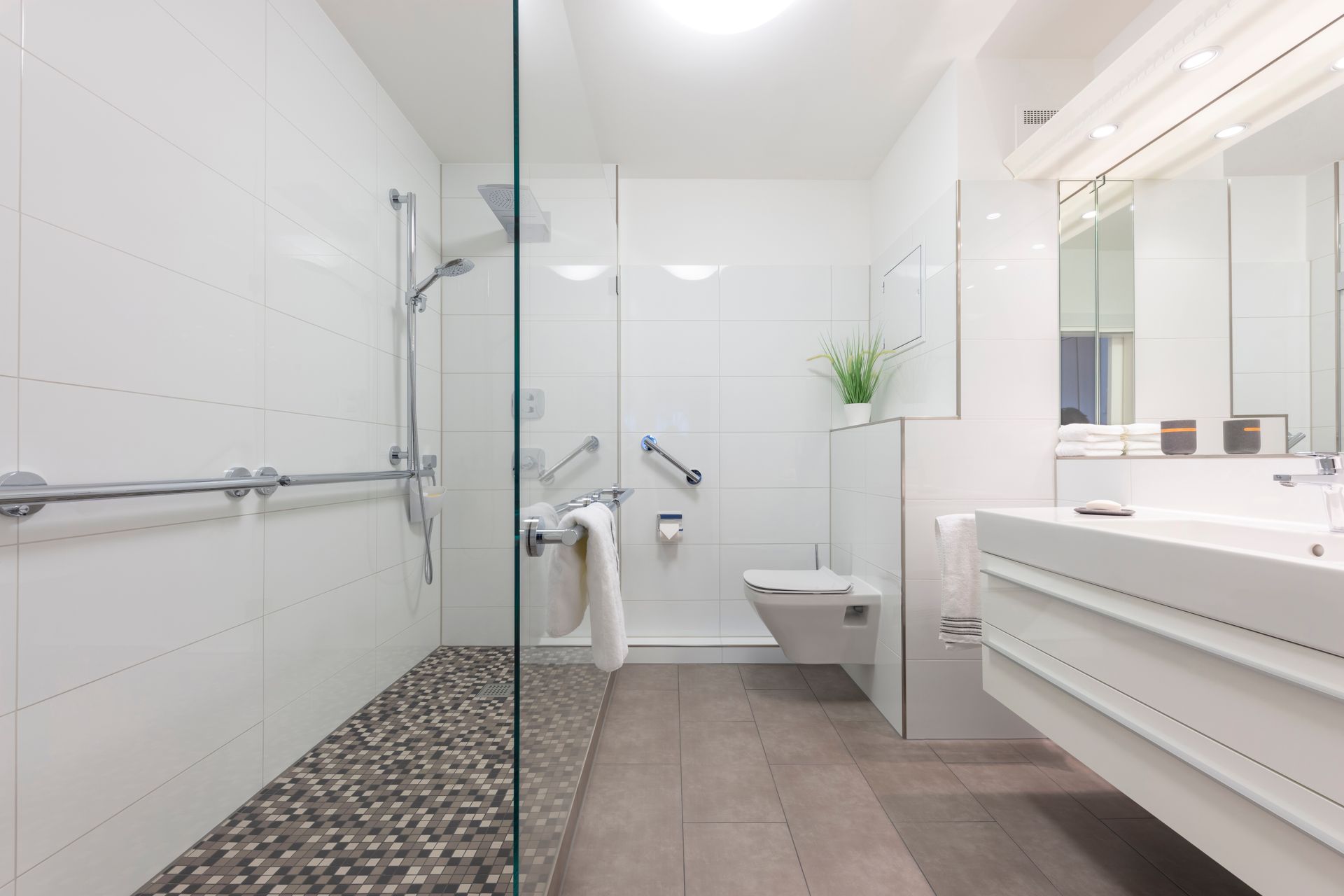 Ein Badezimmer mit ebenerdiger Dusche, Toilette, Waschbecken und Spiegel.