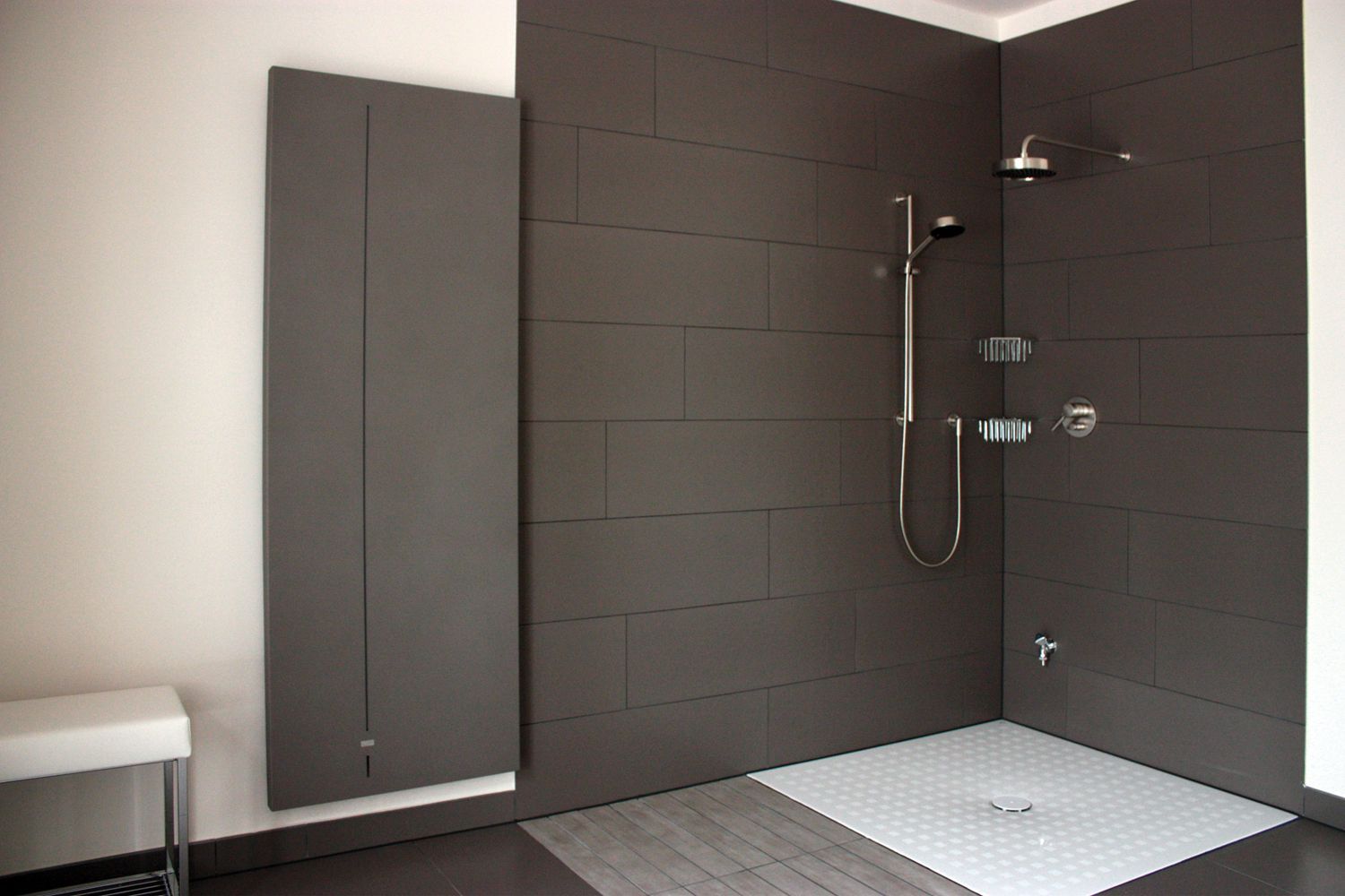 Ein Badezimmer mit ebenerdiger Dusche und einer Sitzbank.