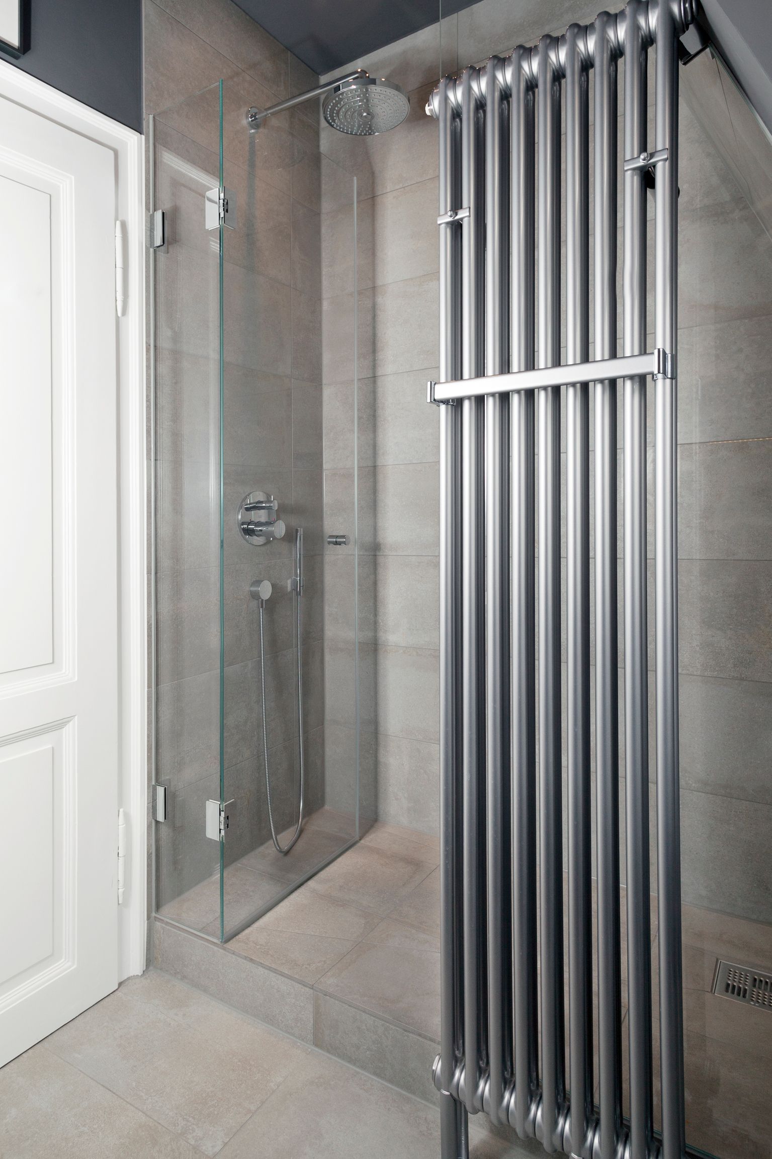 Ein Badezimmer mit einer Glasduschtür und einem Heizkörper.