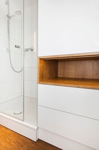 Ein Badezimmer mit ebenerdiger Dusche und einem Holzregal.
