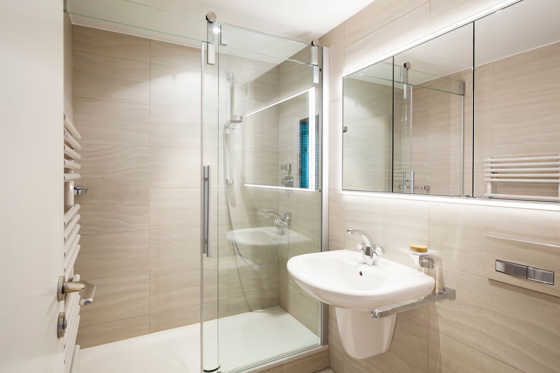 Ein Badezimmer mit Waschbecken, Spiegel und ebenerdiger Dusche.