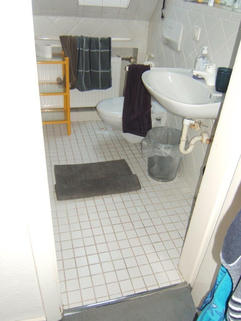 Ein Badezimmer mit Toilette, Waschbecken und Mülleimer