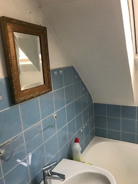 Ein Badezimmer mit blauen Fliesen, einem Waschbecken und einem Spiegel