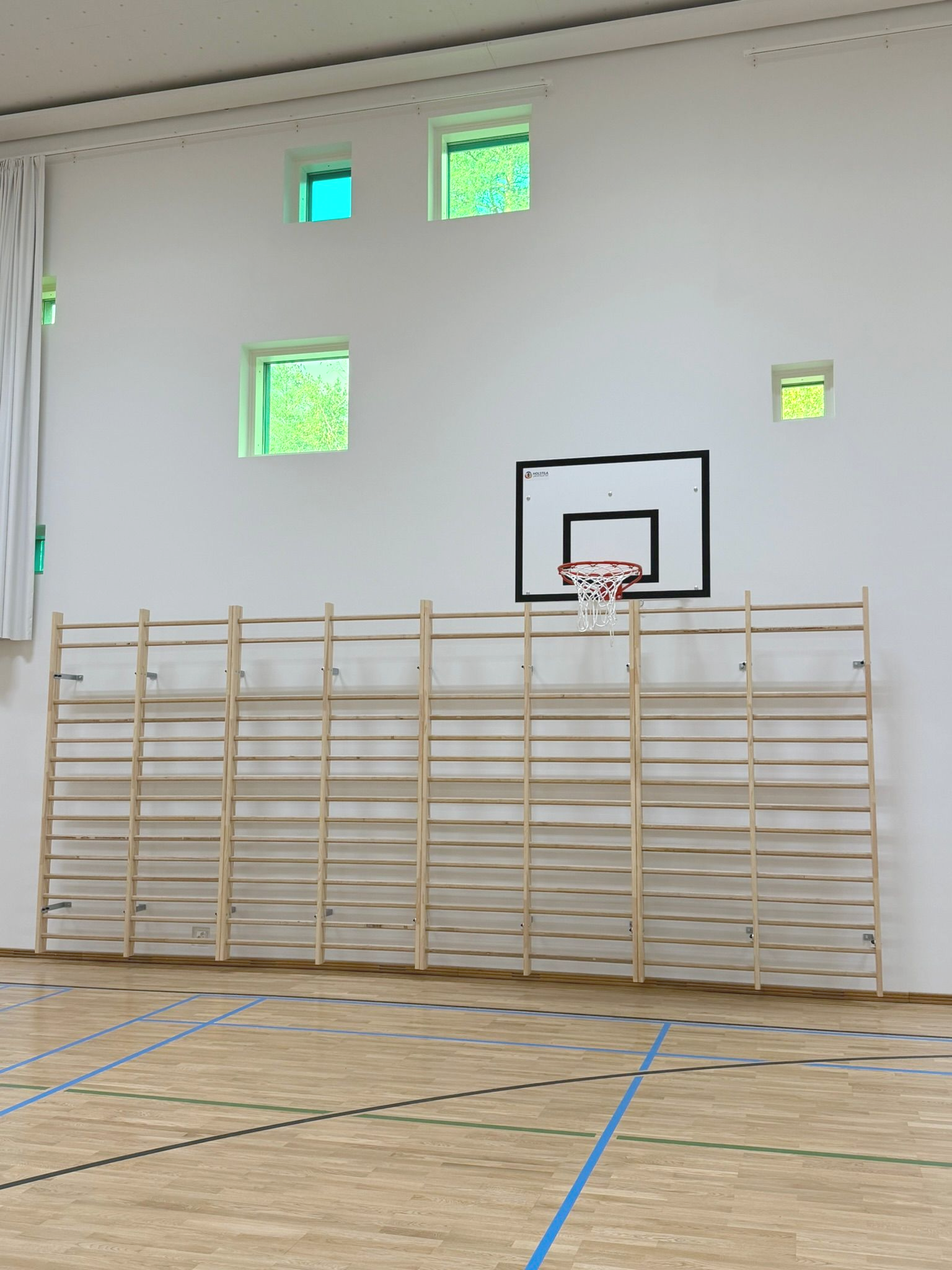 Liikuntalattiat Holstila asentamat liikuntasalin välineet - koripallotelineet, voimistelurenkaat ja puolapuut. Koulun urheiluhalliin suunnitellut välineet ovat turvallisia, kestäviä ja täyttävät kaikki standardit.
Kuvassa kaasujousellinen koripalloteline ja puolapuut.