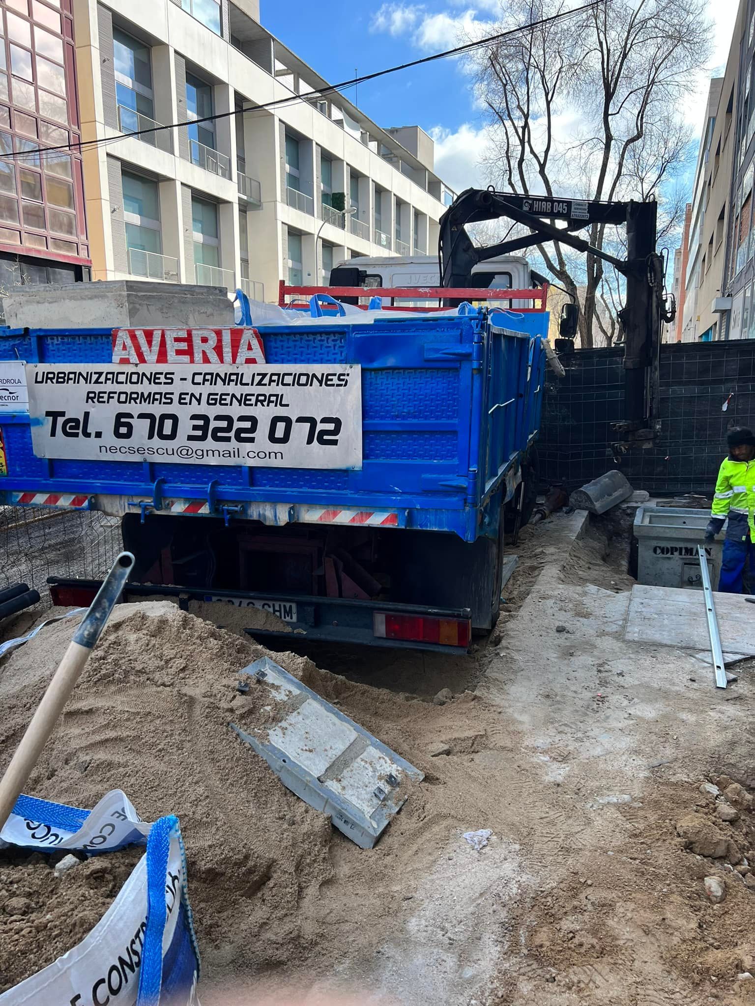 Un camión azul está estacionado al costado de la carretera al lado de un montón de tierra.