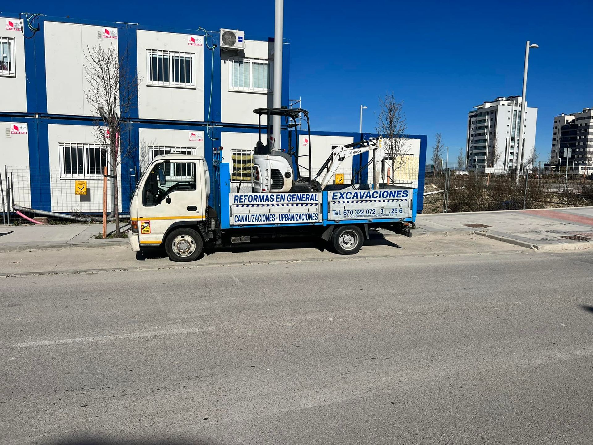 Un camión azul y blanco está estacionado al costado de la carretera.