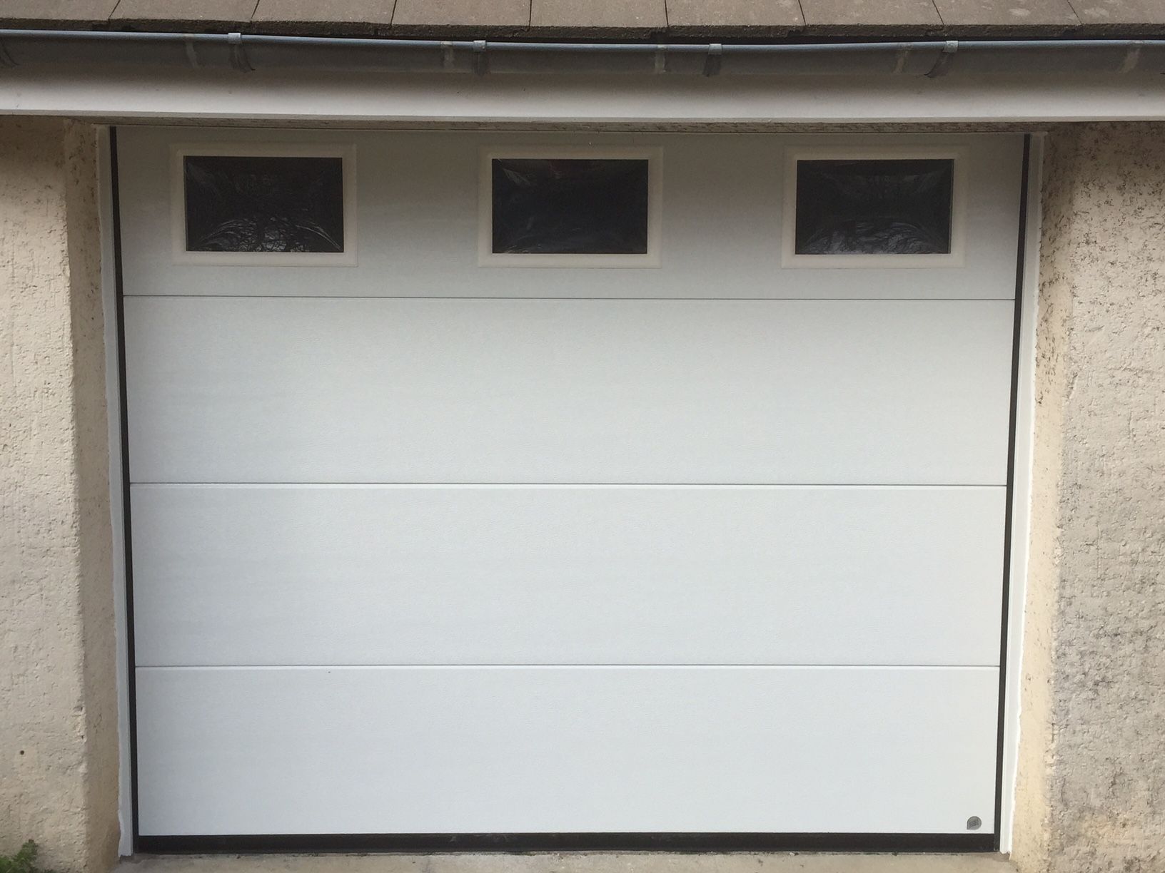 Une porte de garage blanche à ouverture sectionnelle verticale.