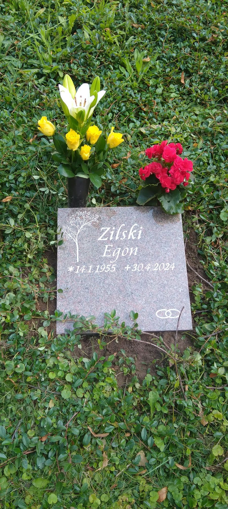 Ein Grabstein mit Blumen darauf auf einem Friedhof.