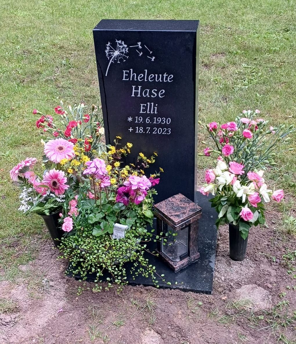 Ein schwarzer Grabstein mit Blumen und einer Laterne darauf