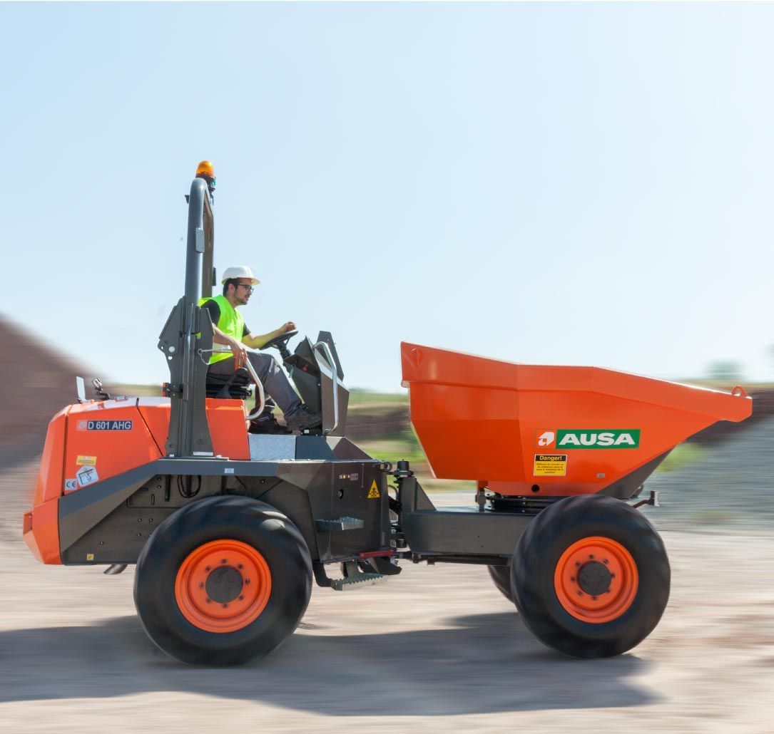 Camion-benne orange AUSA avec un ouvrier au volant. Le camion se trouve sur un chantier.