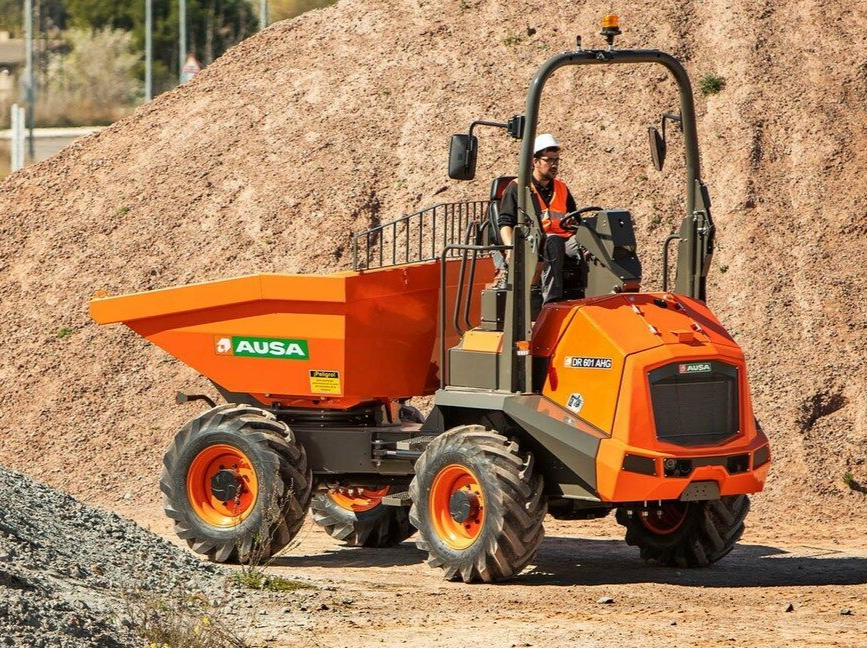 Camion-benne orange AUSA sur un tas de terre, un ouvrier dans la cabine le manœuvre.