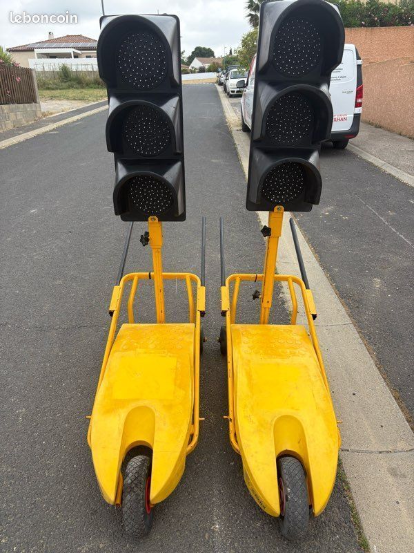 Deux feux de circulation portables jaunes dans une rue, chacun comportant trois feux de signalisation noirs.