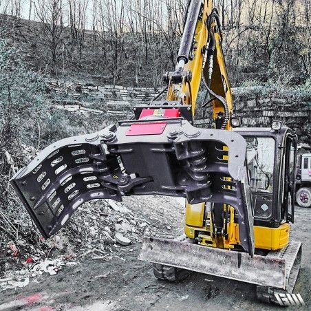 Pelle mécanique jaune équipée d'une grande pince, en extérieur sur un chantier de construction.