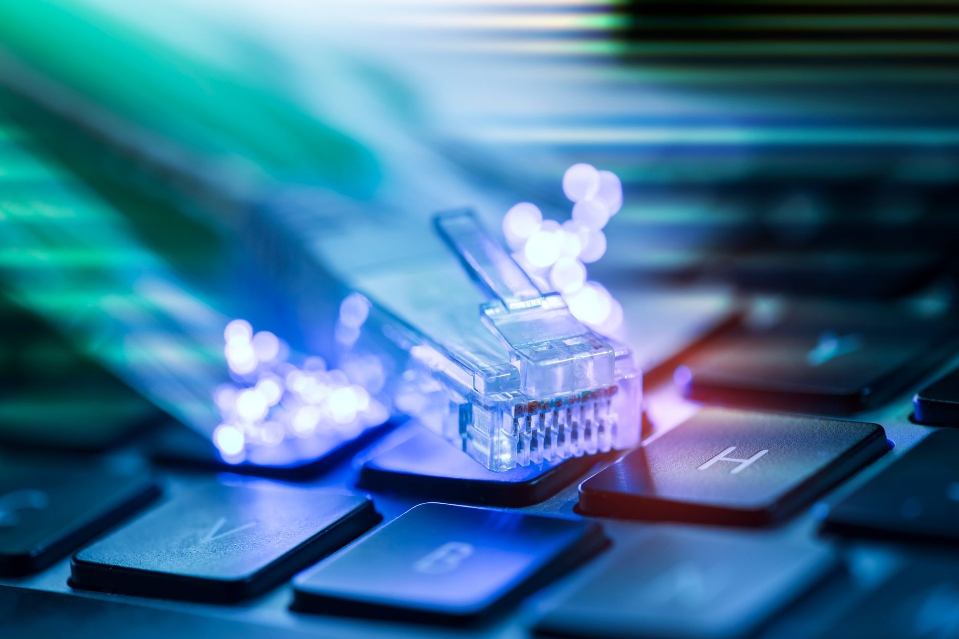 Un primer plano de un teclado de computadora con un cable Ethernet conectado a él.
