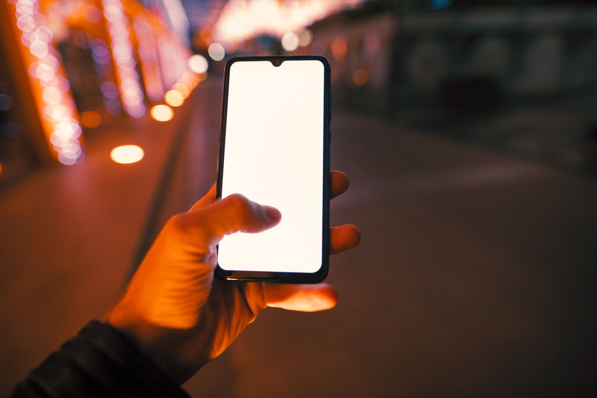 Una persona sostiene un teléfono celular con una pantalla blanca en su mano.