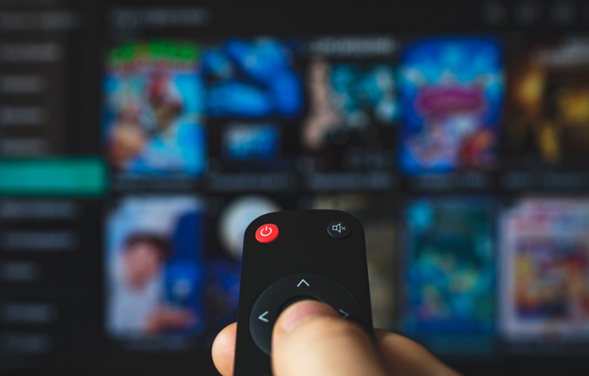 Una persona sostiene un control remoto frente a una pantalla de televisión.