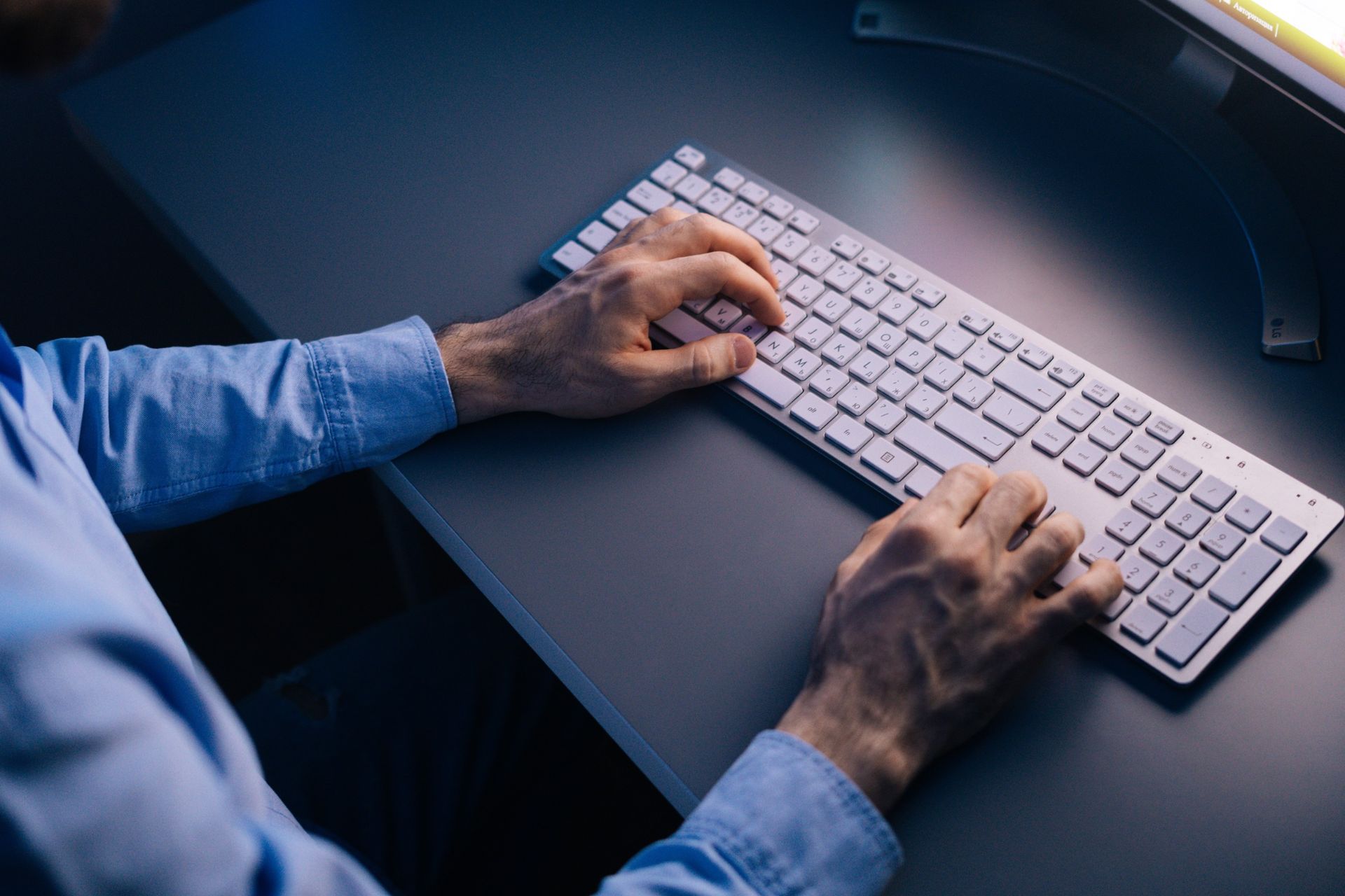 Un hombre está escribiendo en un teclado de computadora.