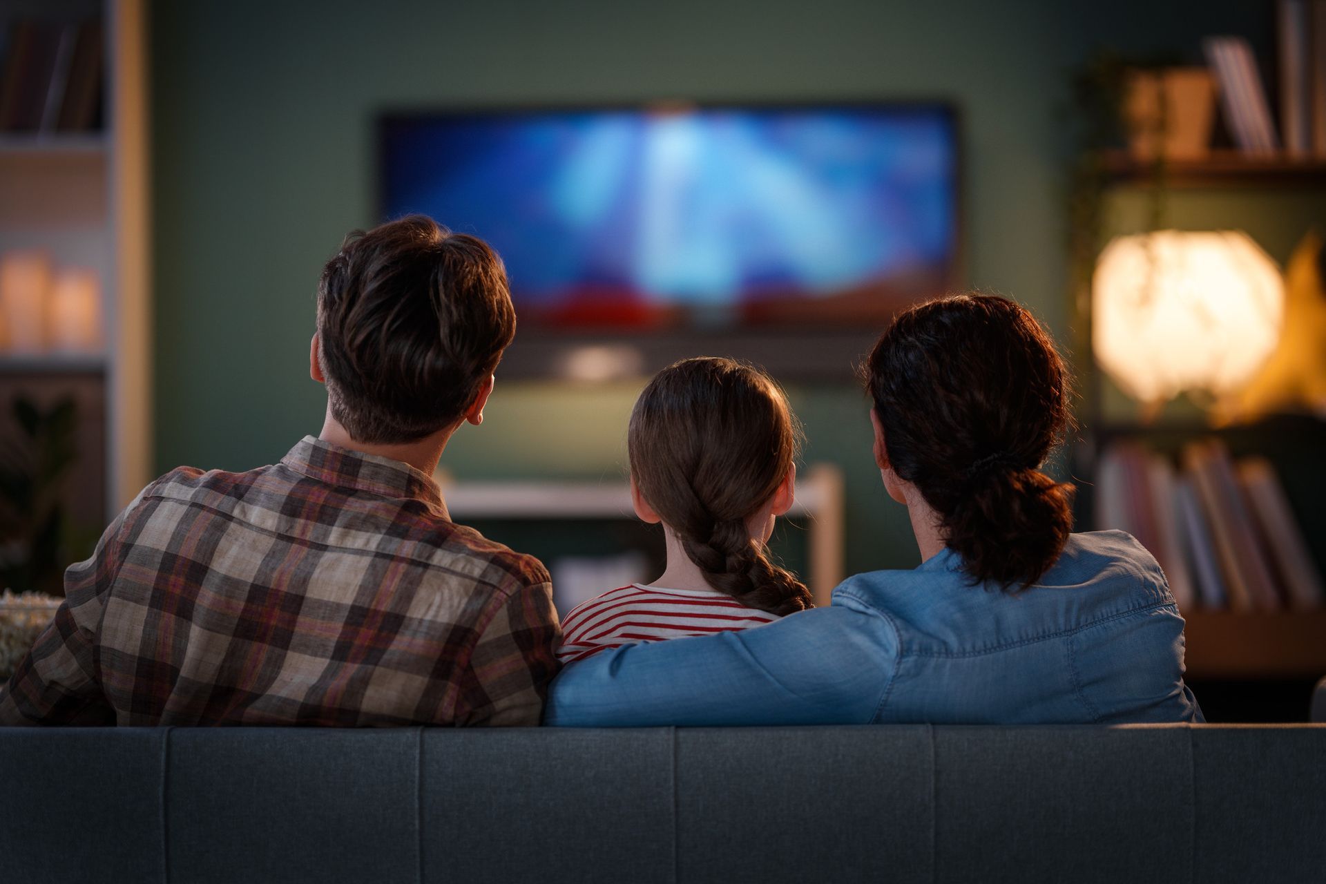 Una familia está sentada en un sofá viendo la televisión.