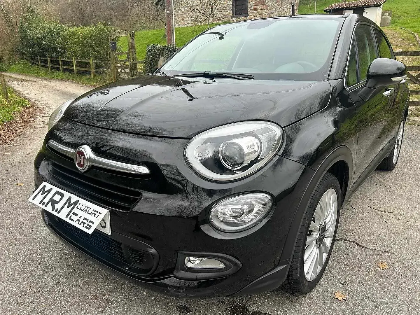 Un coche negro está aparcado al costado de la carretera.