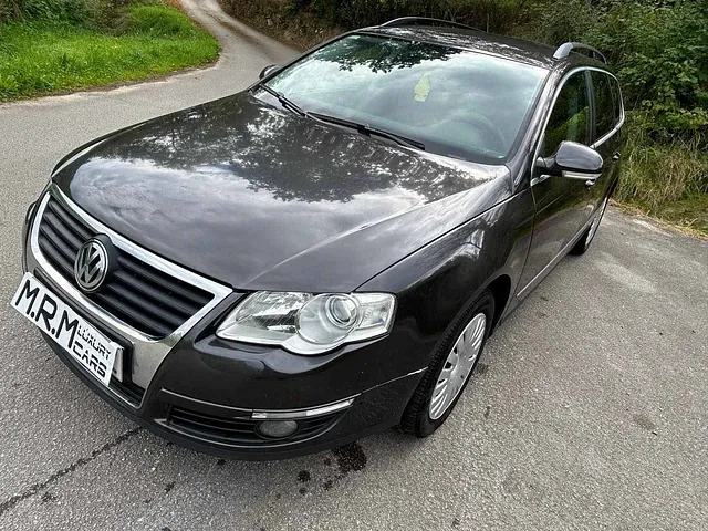 Un Volkswagen Passat negro está estacionado al costado de una carretera.