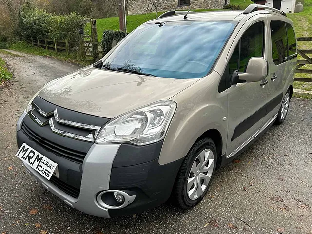 Un Citroën Berlingo está estacionado al costado de un camino de tierra.