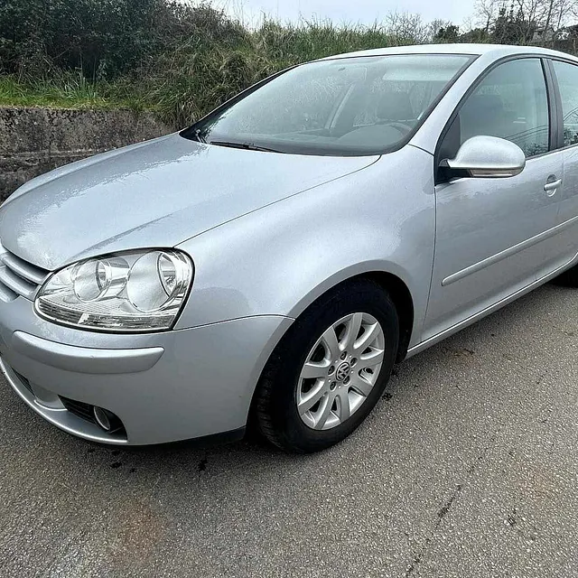 Un coche plateado está aparcado al costado de la carretera.