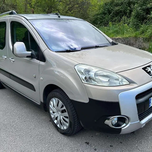 Una camioneta plateada y negra está estacionada al costado de la carretera.