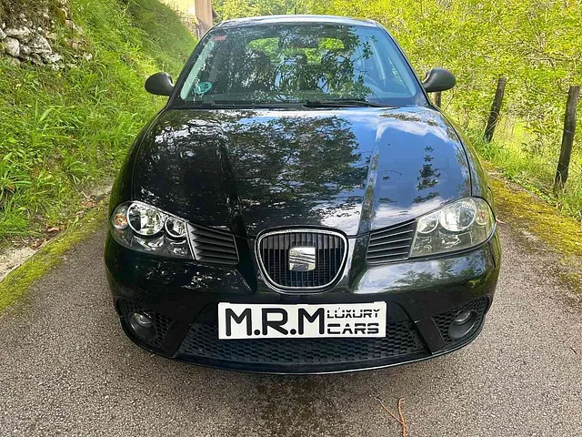 Un coche negro está aparcado al costado de una carretera.