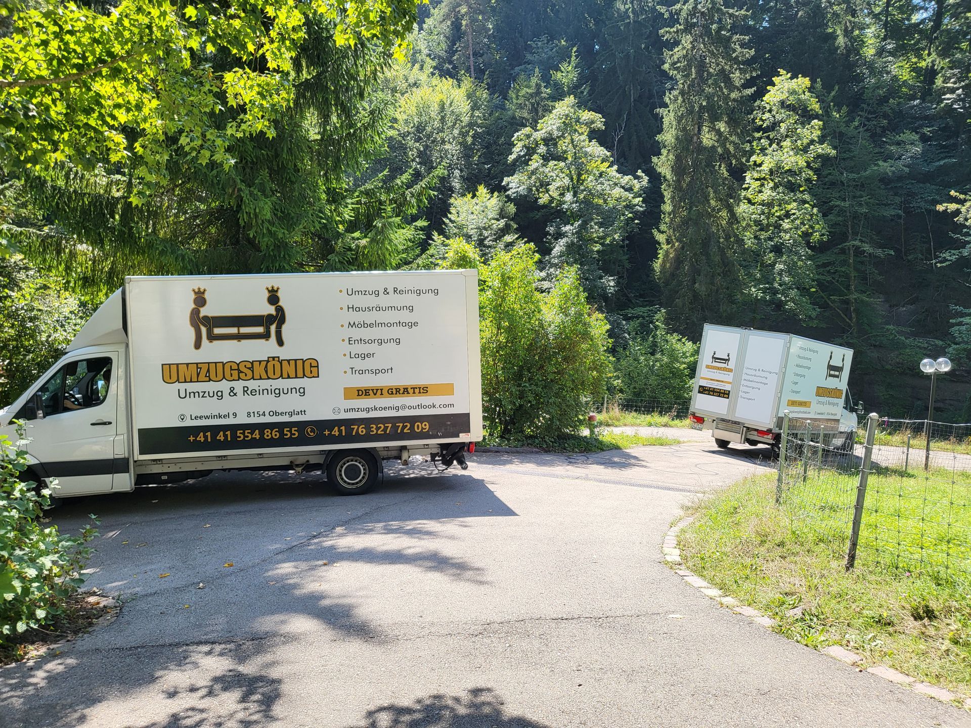 Ein weisser Lieferwagen fährt an einem hellen, sonnigen Tag auf einer Autobahn; im Hintergrund sind Stadtgebäude zu sehen.