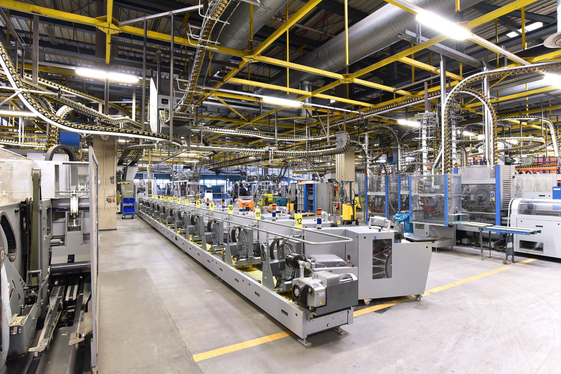 Ligne de production automatisée avec machines et tuyauterie aérienne dans un entrepôt industriel lumineux